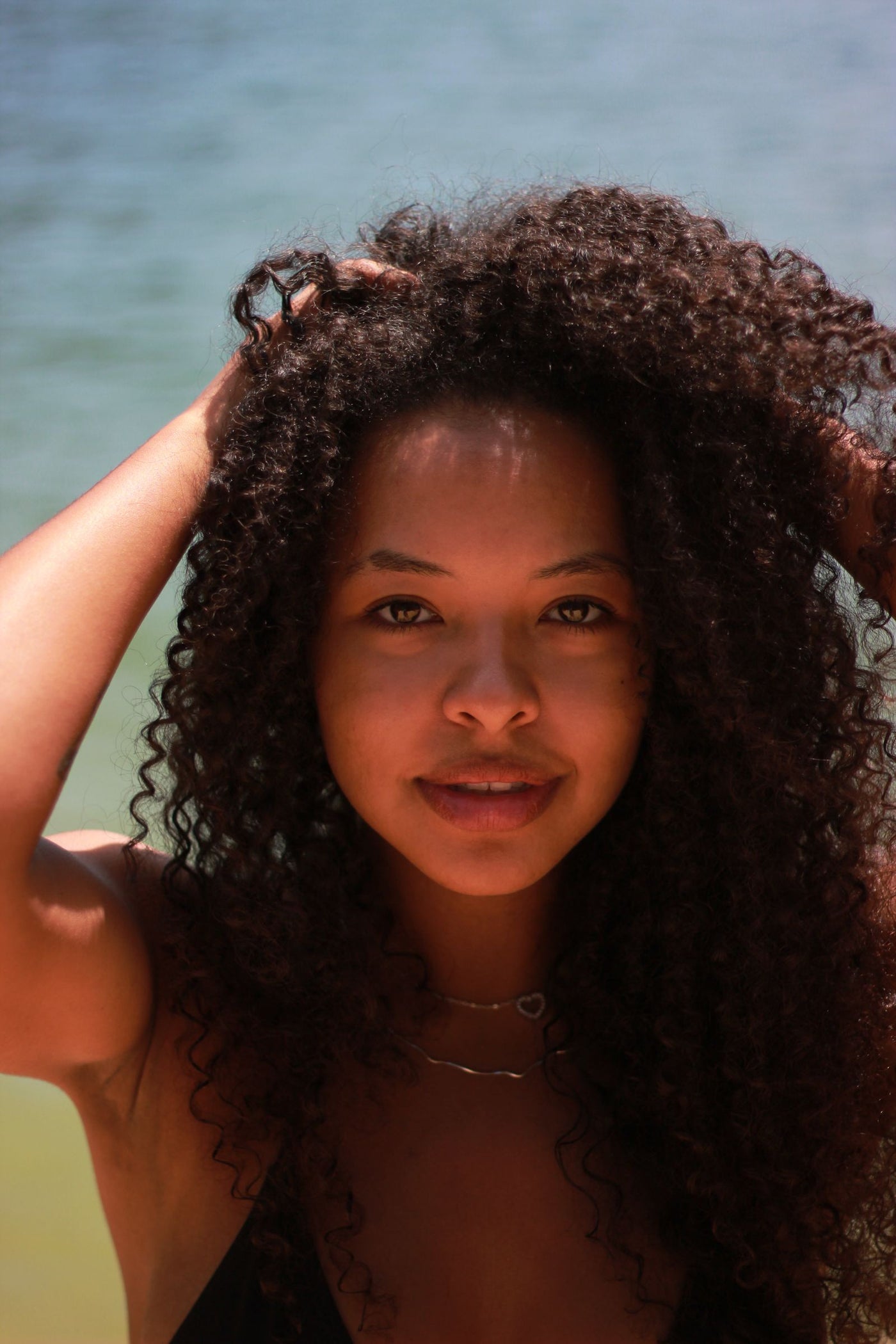 Woman with curly hair at the beach protecting her curls from sun and salt water in summer
