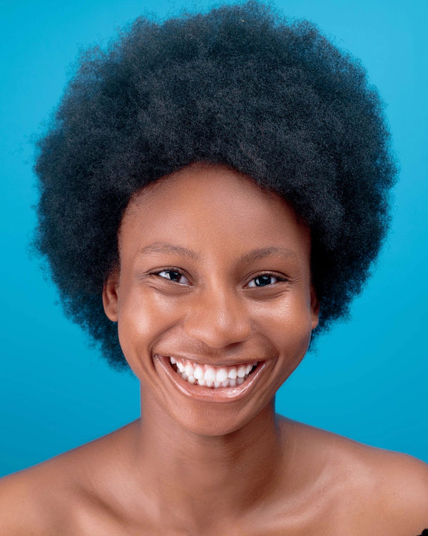 Smiling woman with healthy black curly hair showing balanced protein and moisture in type 3 and 4 textured hair